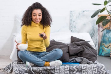 Gıda ile kase tutarak ve evde tv izlerken çok şık Afro-Amerikan Kız