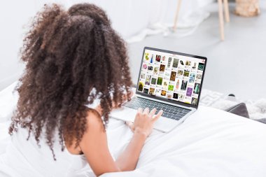Dikiz pinterest evde yatakta ekranda ile dizüstü bilgisayar kullanan kıvırcık kadın