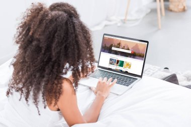 Dikiz shutterstock evde yatakta ekranda ile dizüstü bilgisayar kullanan kıvırcık kadın