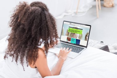 evde yatakta ekranda bbc bilim ile dizüstü bilgisayar kullanan kıvırcık kadın dikiz