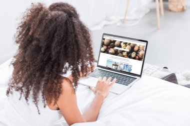 Dikiz depositphotos.com evde yatakta ekranda ile dizüstü bilgisayar kullanan kıvırcık kadın