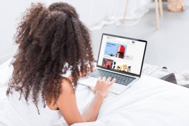 Dikiz ekran evde yatakta ebay ile dizüstü bilgisayar kullanan kıvırcık kadın