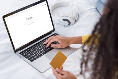 kredi kartı tutan ve ekranda google ile dizüstü bilgisayar kullanarak kadın resim kırpılmış