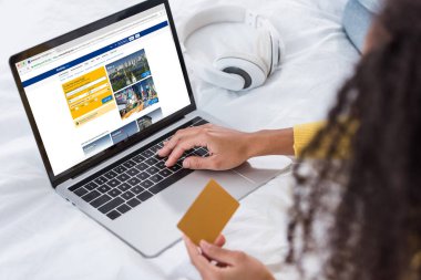 cropped image of woman holding credit card and using laptop with booking on screen clipart
