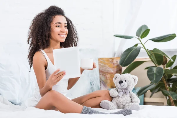 Atractiva Mujer Joven Afroamericana Sosteniendo Taza Café Uso Tableta Digital — Foto de stock gratis