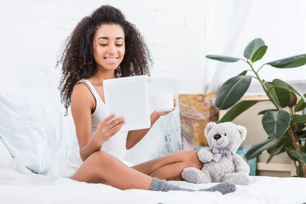 Feliz Afroamericana Joven Mujer Sosteniendo Taza Café Uso Tableta Digital — Foto de stock gratis