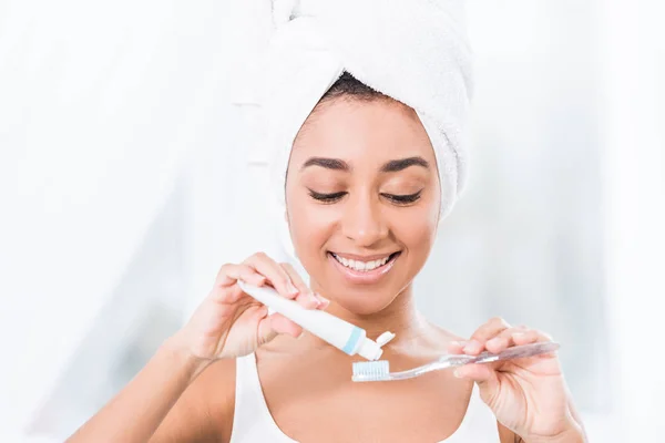 African American Young Woman Towel Wrapped Head Putting Toothpaste Toothbrush — Stock Photo, Image