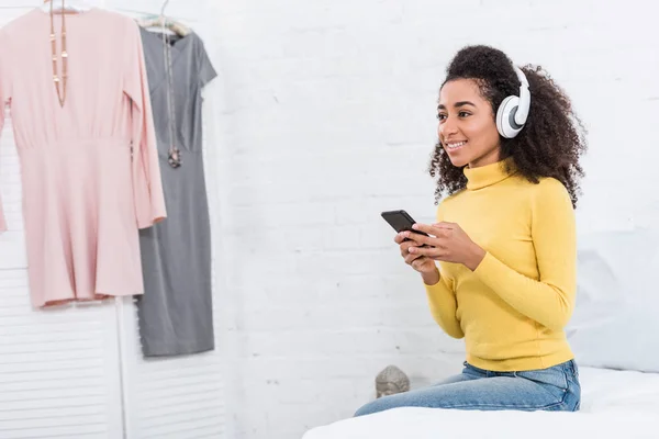 Σγουρά Αφρικανική Αμερικανική Γυναίκα Ακουστικά Ακούγοντας Μουσική Smartphone Στο Σπίτι — Δωρεάν Φωτογραφία