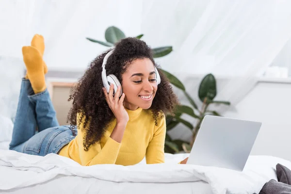 Krullend Afro Amerikaanse Vrouwelijke Freelancer Hoofdtelefoon Werken Laptop Bed Thuis — Stockfoto