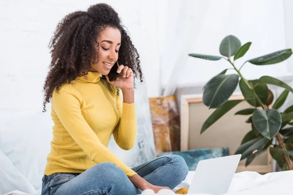 Aantrekkelijke Afro Amerikaanse Vrouwelijke Freelancer Praten Smartphone Werken Laptop Bed — Gratis stockfoto