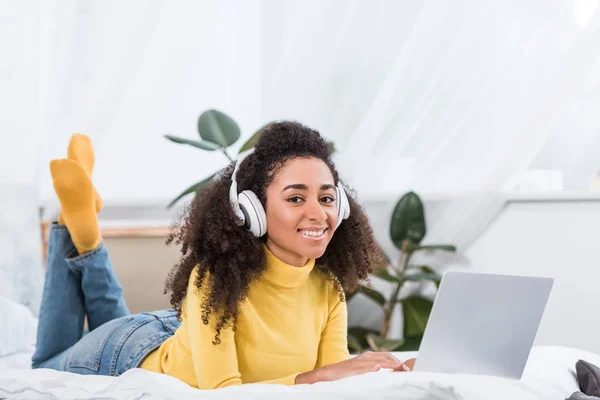 Smiling African American Female Freelancer Headphones Working Laptop Bed Home — Free Stock Photo