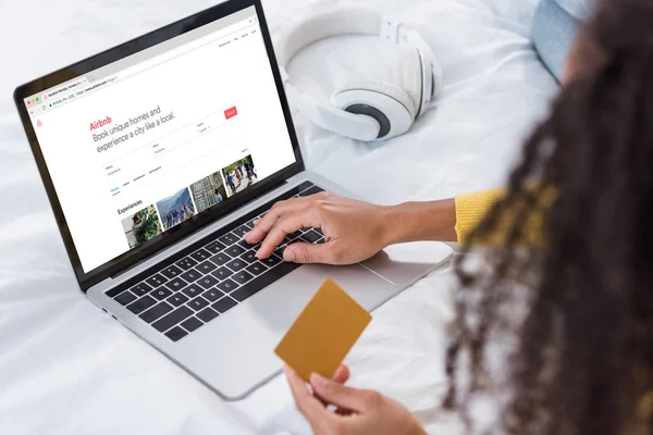 女性のクレジット カードを保持していると Airbnb 画面上でラップトップを使用して画像をトリミング — ストック写真