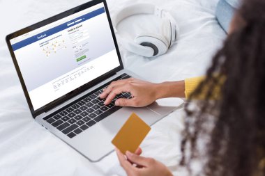 kredi kartı tutan ve dizüstü bilgisayar ekranında facebook ile kullanarak kadın resim kırpılmış