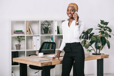 modern ofis Smartphone cep telefonu ile konuşurken kısa saçlı çekici Afro-Amerikan işkadını