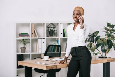 Afro-Amerikan işkadını smartphone modern ofis içinde konuşurken kısa saçlı