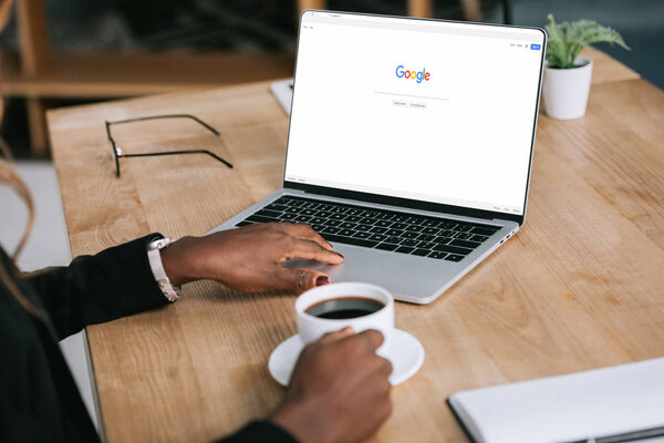 обрезанный вид африканской американки с помощью ноутбука с браузером Google возле чашки кофе
