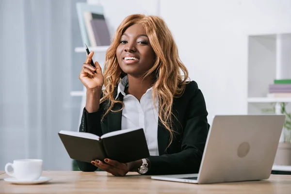 Mujer Negocios Afroamericana Feliz Sosteniendo Cuaderno Pluma Oficina Moderna — Foto de stock gratis