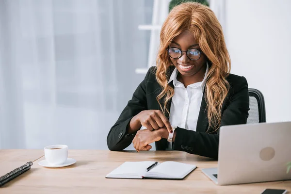 Alegre Mujer Negocios Afroamericana Sentada Gafas Mirando Reloj — Foto de stock gratuita