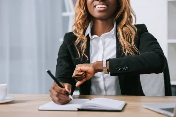 Cropped View African American Woman Looking Watch Writing Notebook — Free Stock Photo