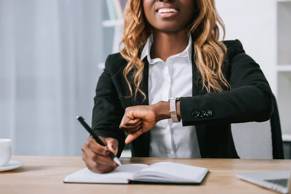 Vista Recortada Mujer Afroamericana Mirando Reloj Escritura Cuaderno — Foto de stock gratis