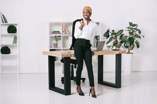 Veselá Africká Americká Podnikatelka Krátkými Vlasy Drží Bunda Moderní Kanceláři — Stock fotografie zdarma