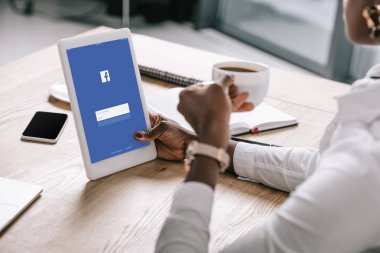 Dijital tablet facebook app ve kahve ile tutan Afrikalı-Amerikalı kadın görünümünü kırpılmış