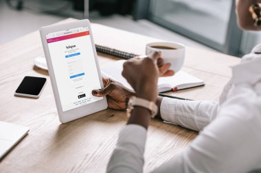 Dijital tablet instagram app ve kahve ile tutan Afrikalı-Amerikalı kadın görünümünü kırpılmış