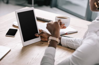 Kırpılan Kupası ve dijital tablet ile boş perde tutan Afrikalı-Amerikalı kadın görünümünü 