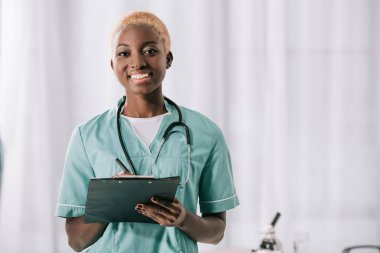 smiling african american woman with stethoscope and clipboard clipart
