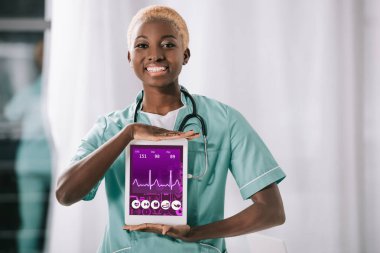 Dijital tablet kalp atışı oranı ile ekranda elinde stetoskop ile neşeli Afro-Amerikan hemşire