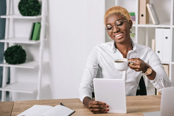 Alegre Mujer Negocios Afroamericana Sosteniendo Taza Con Bebida Tableta Digital — Foto de stock gratuita