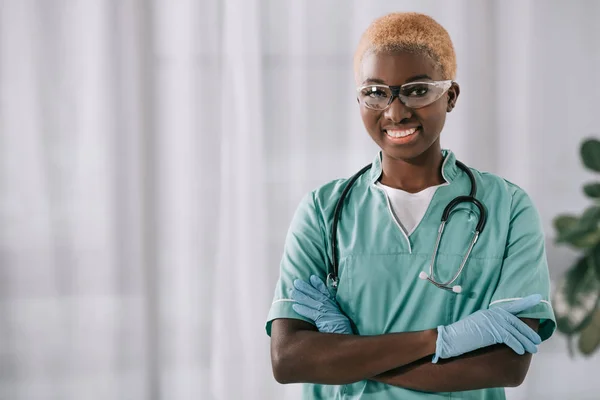 Усміхнена Афроамериканська Медсестра Рукавичках Стоять Схрещеними Руками Дивлячись Камеру — стокове фото