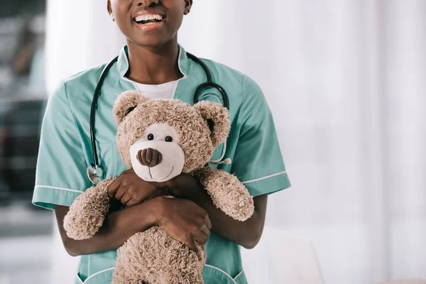 Visão Recortada Sorridente Enfermeira Afro Americana Com Estetoscópio Segurando Ursinho — Fotografia de Stock