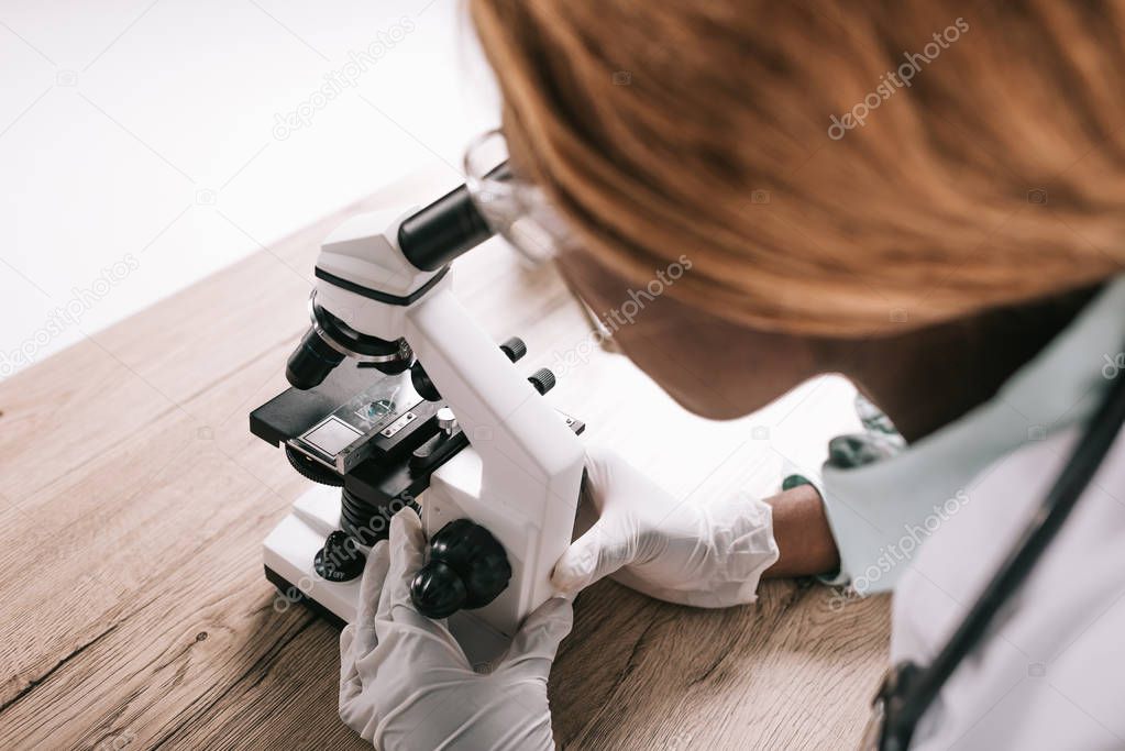 cropped view of female african american scientist looking through microscope