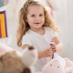 Adorable kid playing with rabbit toy in children room and looking at camera