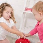 Очаровательные сестры, принимающие аптечку в детской комнате Очаровательные сестры, принимающие аптечку в детской комнате