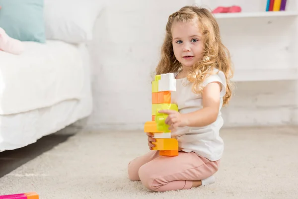 愛らしいキッドの子供部屋カーペットの着色されたプラスチック コンス トラクターで遊んで カメラ目線 — ストック写真