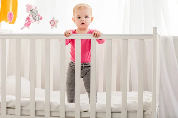 Adorable Kid Pink Shirt Standing Crib Looking Camera — Stock Photo, Image