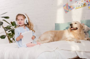çok güzel çocuk çocuk odası yatakta yatan tablet, golden retriever ile müzik dinleme