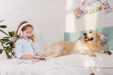 çok güzel çocuk çocuk odası yatakta yatan tablet, golden retriever ile müzik dinleme