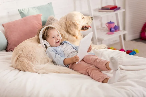 Sonriente Adorable Niño Escuchando Música Con Tableta Apoyándose Golden Retriever —  Fotos de Stock