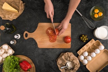 gri arka plan üzerinde pizza malzemeleri ile kesme tahtası üzerinde domates doğrama kadın görünümünü kırpılmış 