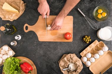 cropped view of man chopping mushroom on cutting board with pizza ingredients on grey background  clipart