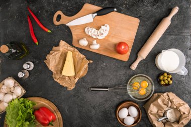 gri arka plan üzerinde pizza malzemeleri ve mutfak aletleri üstten görünüm 