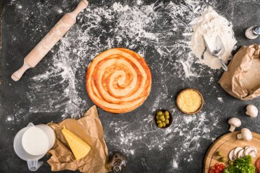 un ile gri arka plan üzerinde pişmemiş pizza, malzemeler ve oklava üstten görünüm 