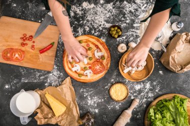 pizza unu ile gri arka plan üzerine malzemeler koyarak kadın kısmi görünümünü 