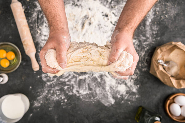 selective focus of man preparing dough on grey background with flour