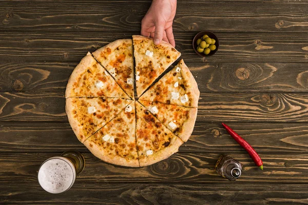 ビールとオリーブの木製のテーブルにチーズのピザを食べている男の部分ビュー — ストック写真