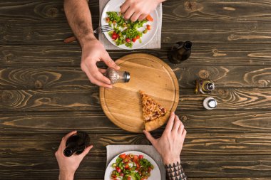 ahşap masa yemek sırasında dilim pizza baharat erkeklerin kırpılmış görünümü
