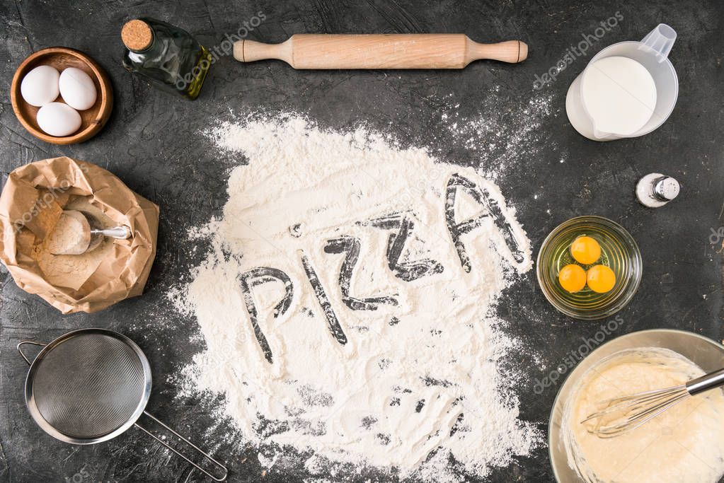 top view of 'pizza' word made of flour with ingredients and cooking utensils on grey background